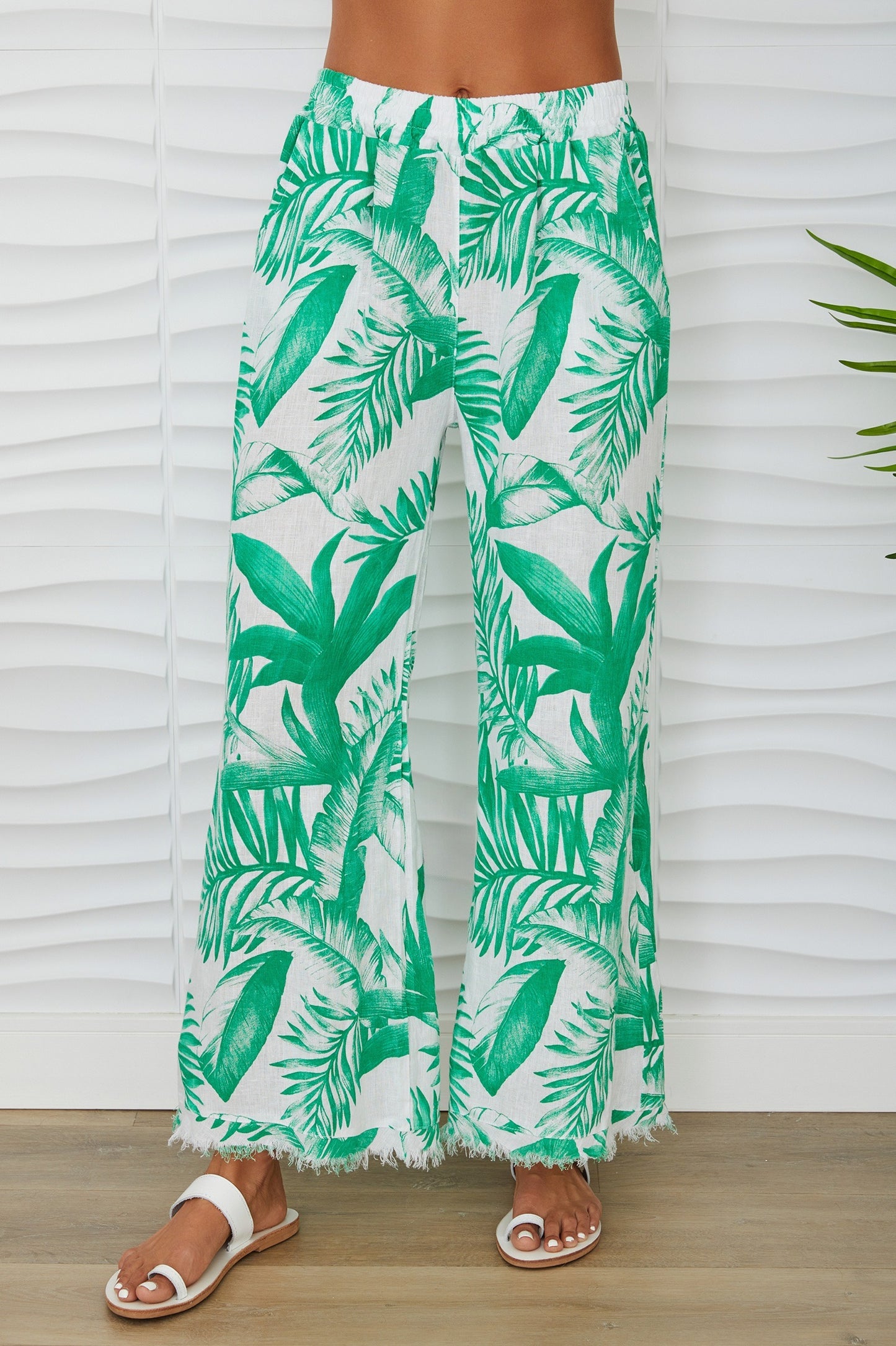 Tropical leaf patterned pants worn by a person against a white background