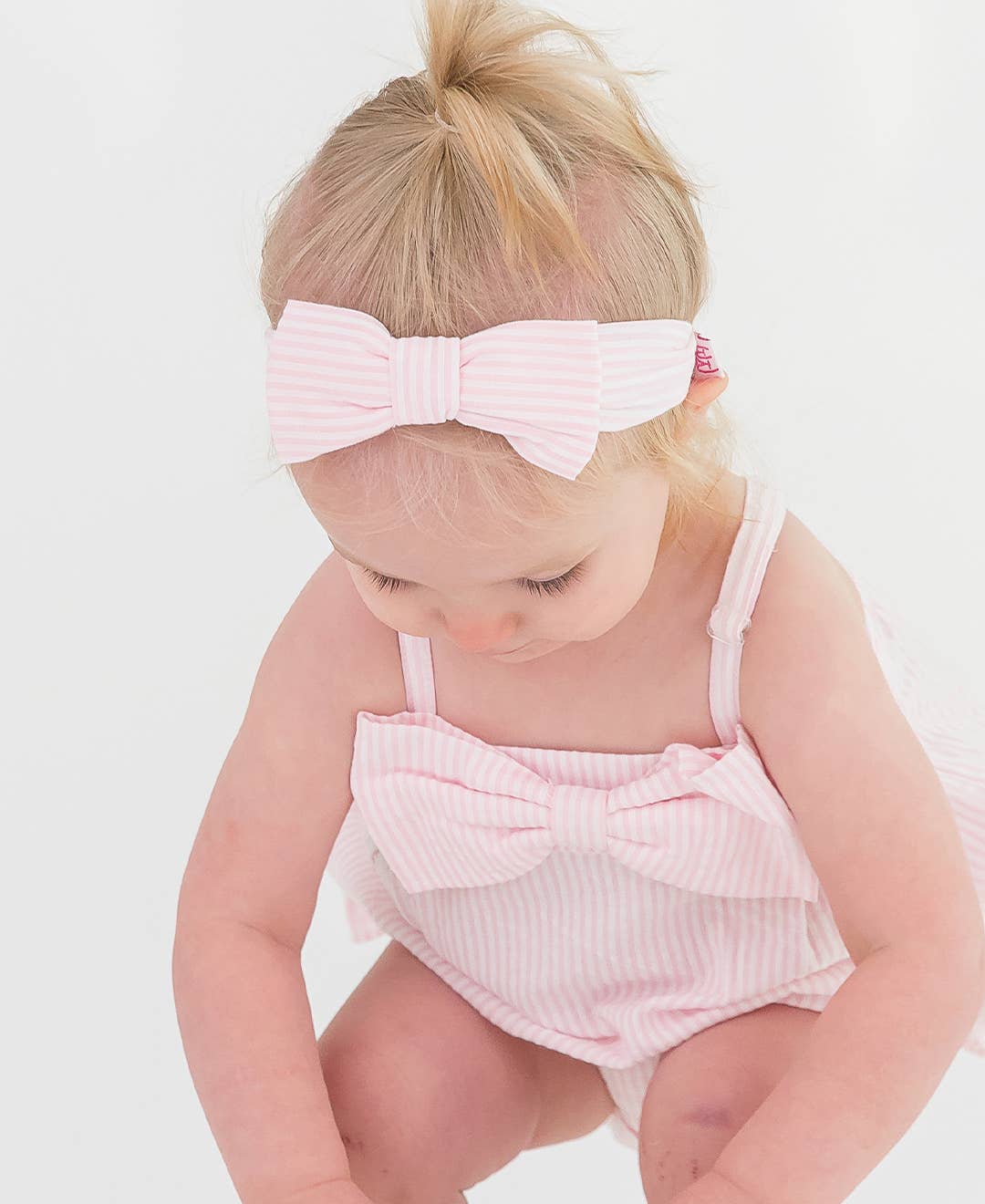 RuffleButts + RuggedButts - Baby Girls Pink Seersucker Bow Front Bubble Woven Romper